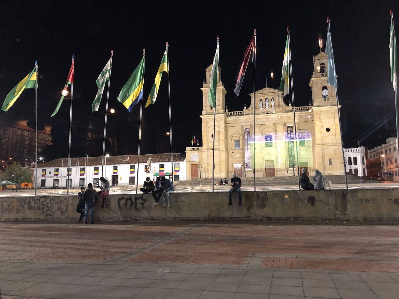 La Basílica de Chiquinquirá iluminada de noche, con las banderas de la plaza