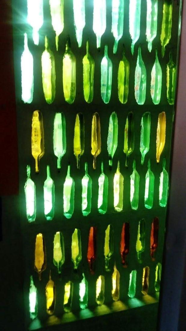 Muro de botellas verdes y ámbar que deja pasar la luz