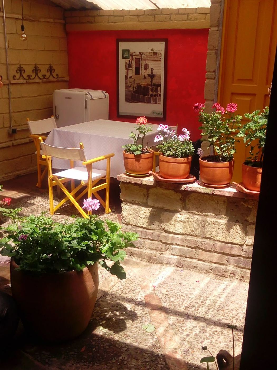 Mesa servida en el patio junto a los geranios