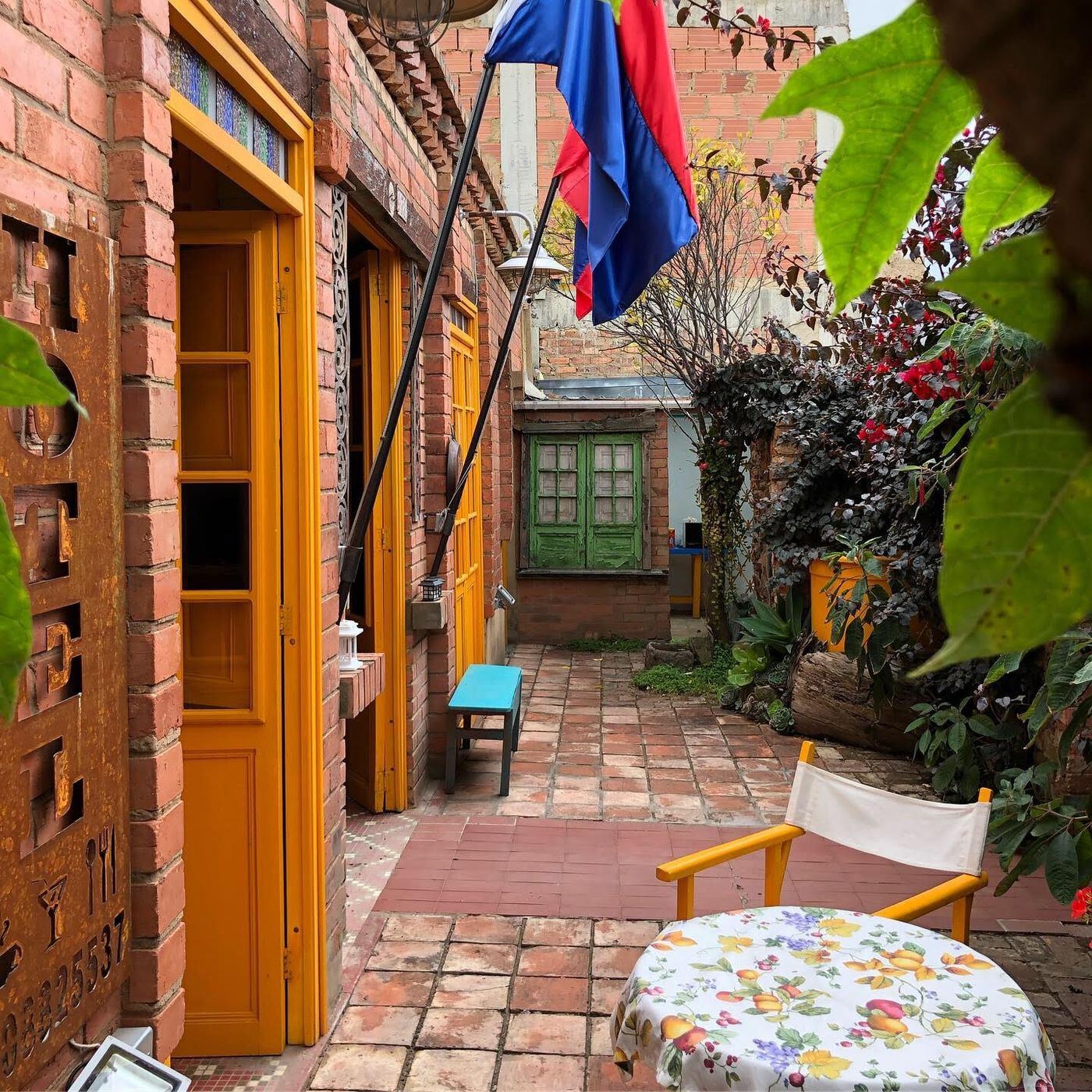 Terraza de ladrillo con puertas amarillas y mesa de mantel floreado